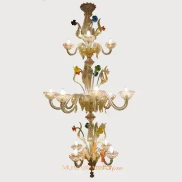 Large glass chandelier with three tiers, clear curved arms, and colorful glass flowers, lit with exposed bulbs on each level.